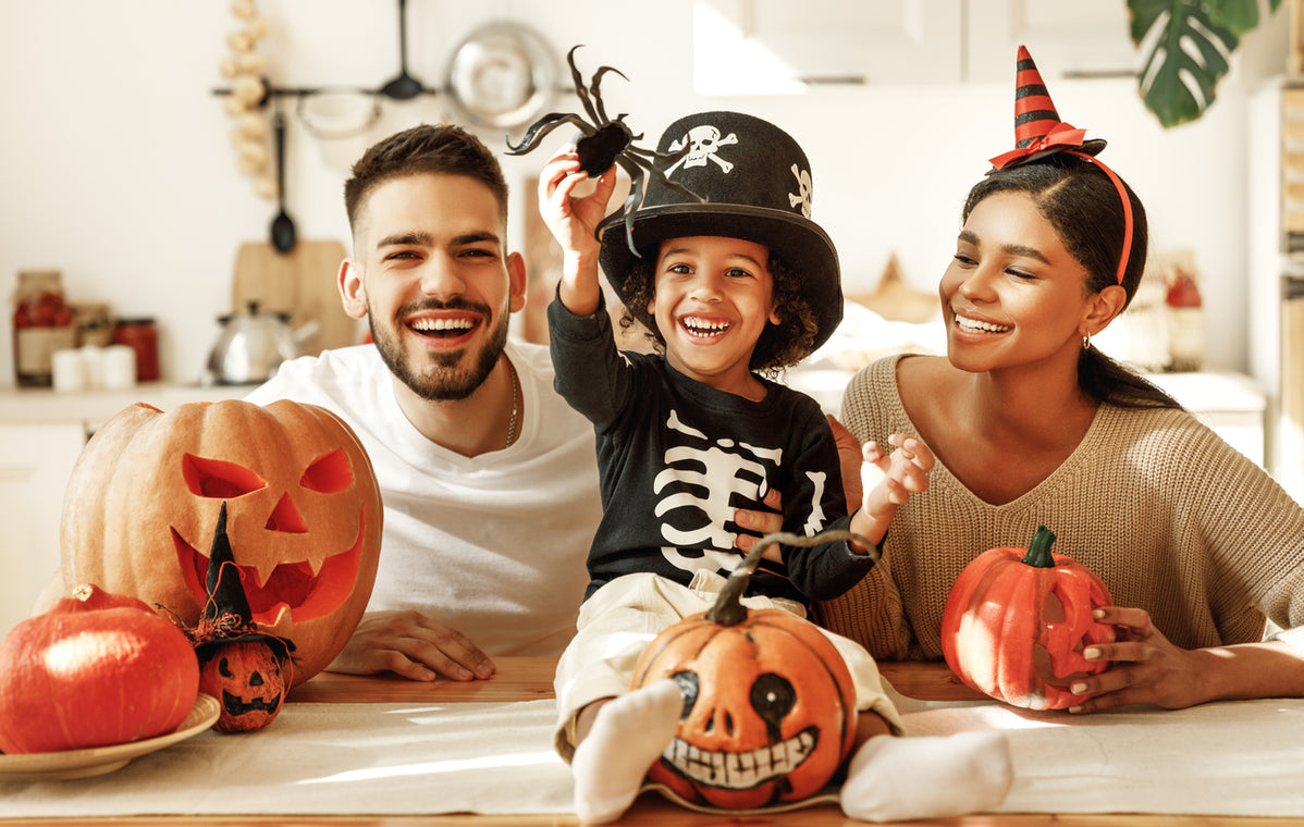 Cheerful parents with son smiling while carving a pumpkin during Halloween while enjoying Zing Bar Minis