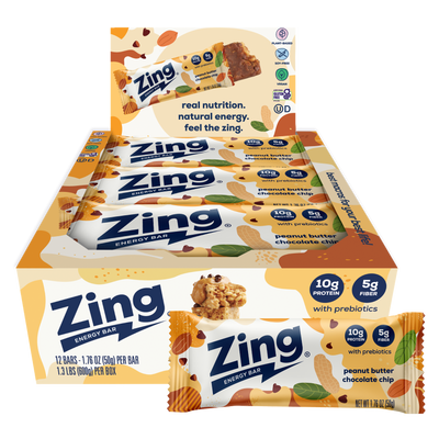 A display box and individual wrapped Zing Energy Bar snack bars on a plain white background. The packaging features orange, white, and blue colors with illustrations of almonds, chocolate pieces, and green leaves, and text indicating peanut butter chocolate chip flavor.
