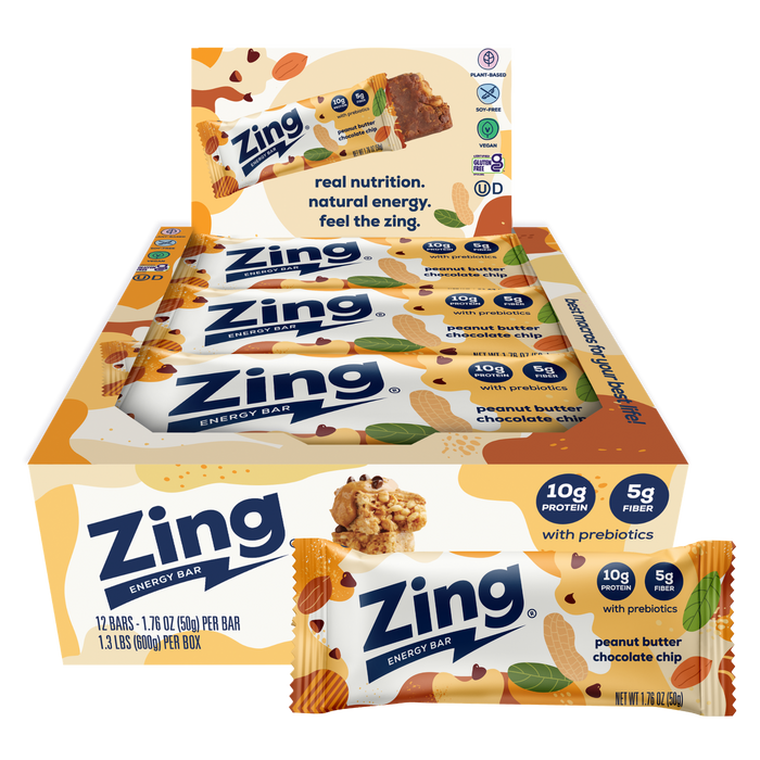 A display box and individual wrapped Zing Energy Bar snack bars on a plain white background. The packaging features orange, white, and blue colors with illustrations of almonds, chocolate pieces, and green leaves, and text indicating peanut butter chocolate chip flavor.