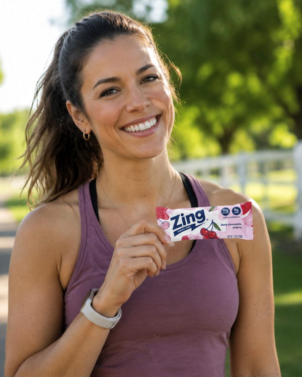 customer holding a dark chocolate cherry zing energy bar after a workout