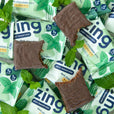 pile of dark chocolate mint mini bars with mint leaves and three bars with bites taken out of them