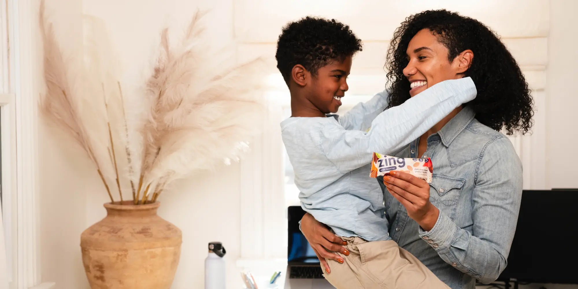 Mom holding her son and a plant-based zing bar